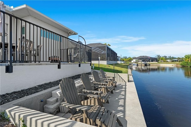 view of patio featuring glass enclosure and a water view