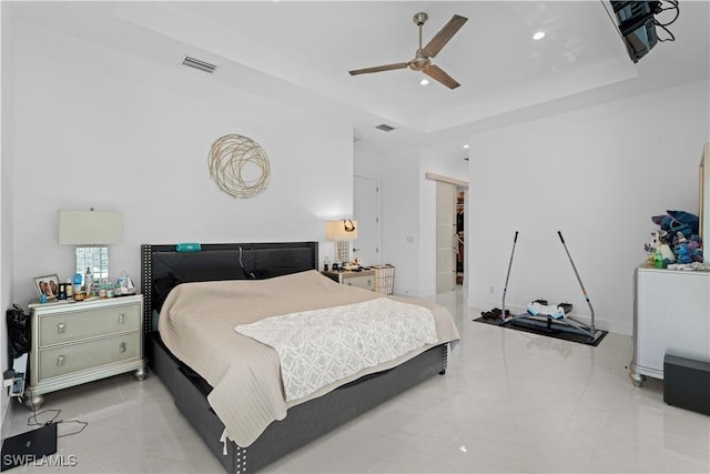 bedroom featuring ceiling fan, a tray ceiling, a closet, and a walk in closet