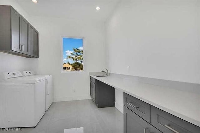 clothes washing area featuring washer and dryer, sink, and cabinets