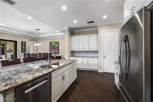 kitchen with pendant lighting, sink, white cabinets, stainless steel appliances, and light stone countertops