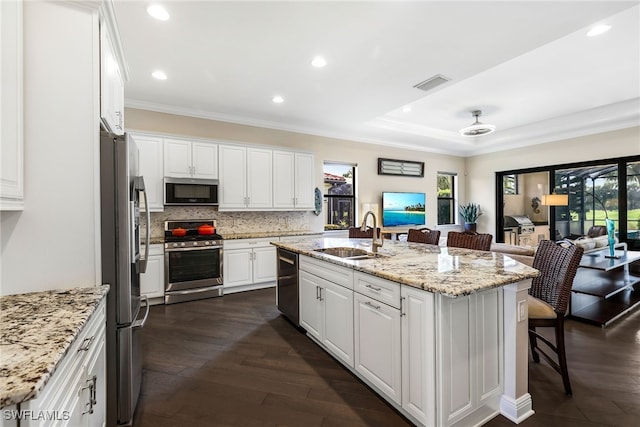 kitchen with an island with sink, appliances with stainless steel finishes, sink, and white cabinets