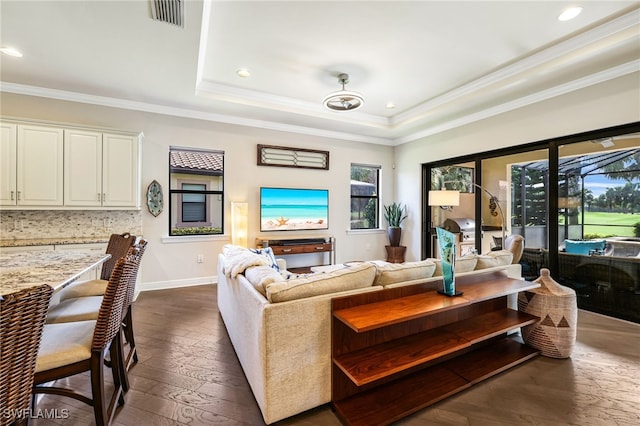 living room featuring a raised ceiling, crown molding, and dark hardwood / wood-style flooring