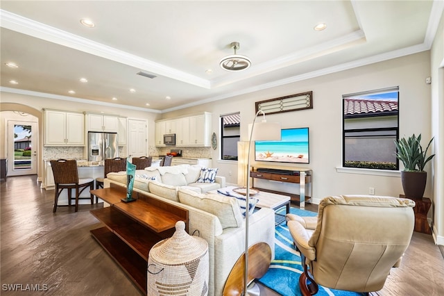 living room with ornamental molding, dark hardwood / wood-style flooring, and a raised ceiling