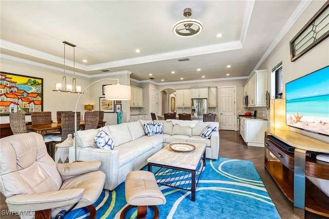 living room featuring a chandelier, ornamental molding, dark hardwood / wood-style flooring, and a raised ceiling