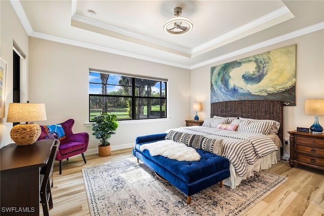 bedroom featuring crown molding, a raised ceiling, and light wood-type flooring