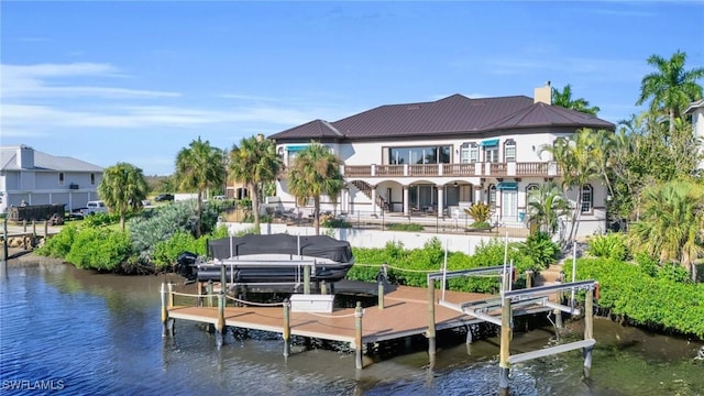 view of dock with a water view, boat lift, and a balcony