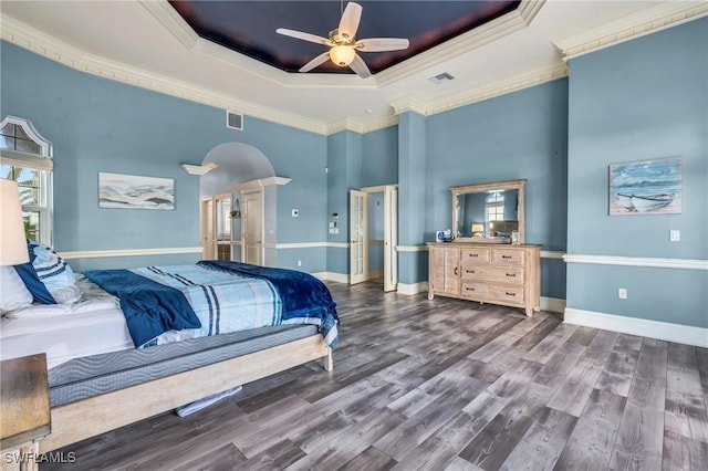 bedroom featuring hardwood / wood-style flooring, a tray ceiling, multiple windows, and crown molding