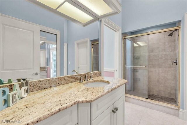 bathroom with a shower with door, vanity, and tile patterned flooring