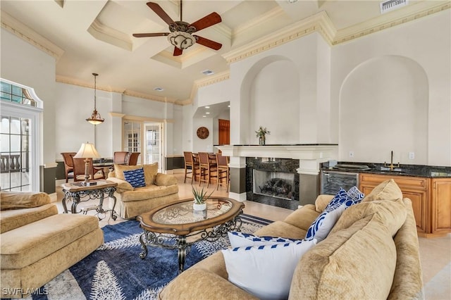 living room featuring coffered ceiling, wet bar, ornamental molding, and a high ceiling