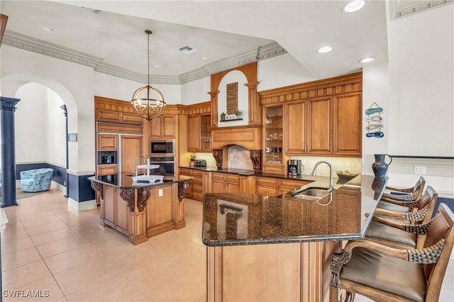 kitchen featuring sink, built in appliances, a breakfast bar, and kitchen peninsula