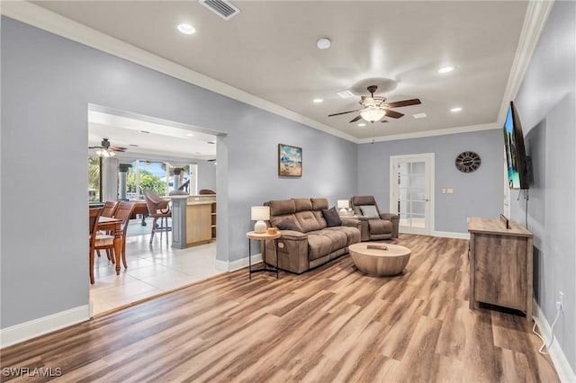 living room featuring crown molding, light hardwood / wood-style floors, and ceiling fan