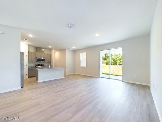 unfurnished living room featuring sink and light hardwood / wood-style floors