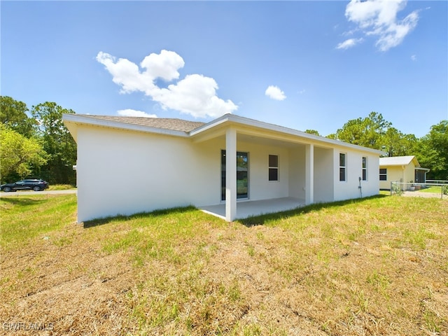 rear view of house featuring a lawn and a patio