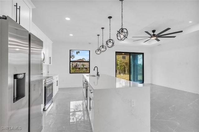 kitchen featuring decorative light fixtures, white cabinetry, sink, a kitchen island with sink, and stainless steel appliances