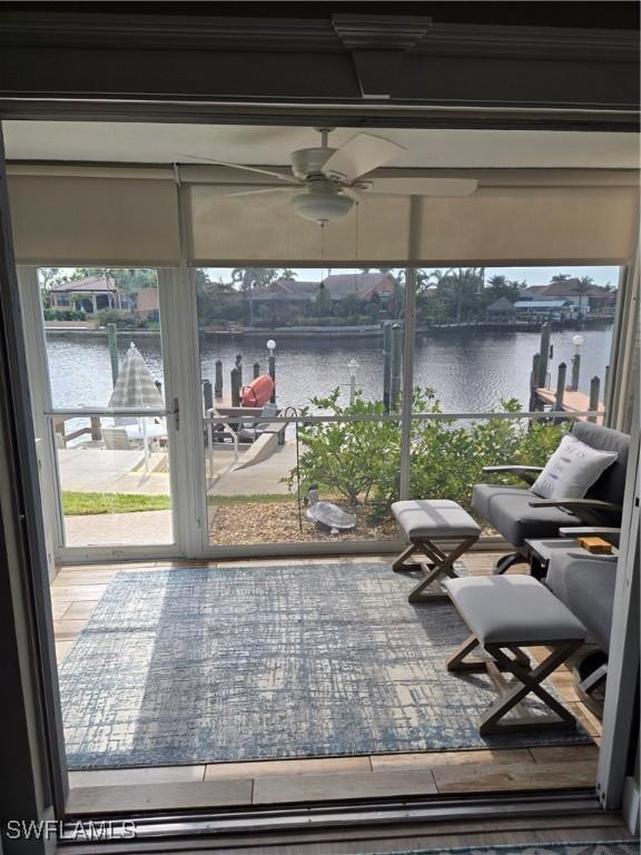 sunroom / solarium with ceiling fan and a water view