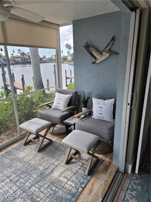 sunroom / solarium featuring ceiling fan and a water view