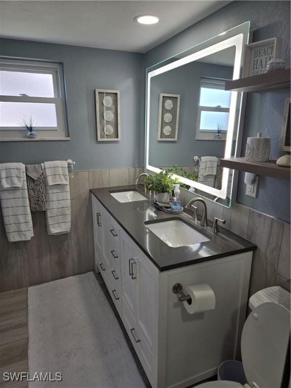 bathroom featuring a healthy amount of sunlight, toilet, vanity, and tile walls