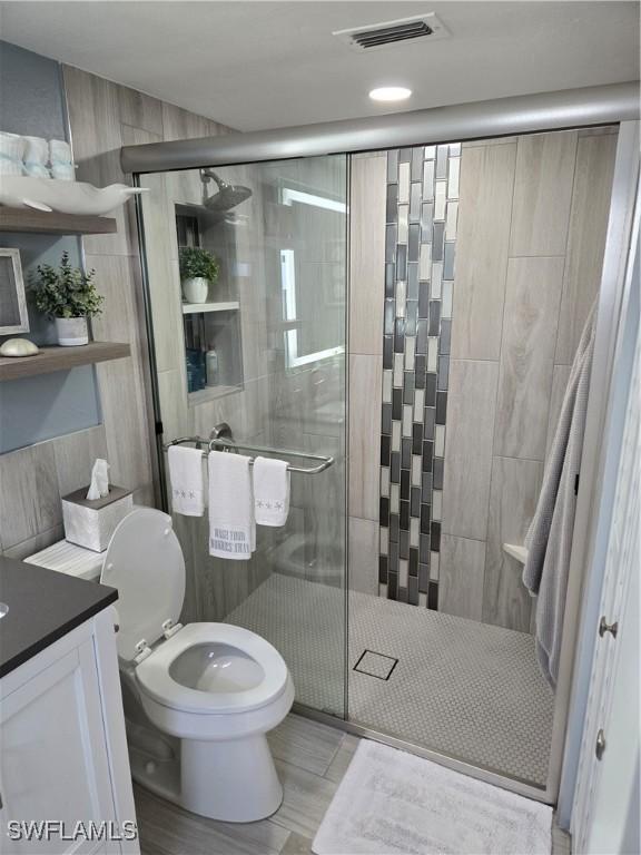 bathroom featuring walk in shower, vanity, and toilet