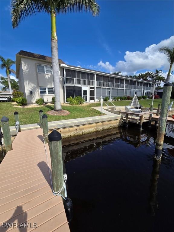 view of dock featuring a lawn and a water view