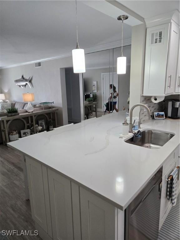 kitchen with dark wood-type flooring, sink, crown molding, hanging light fixtures, and white cabinets