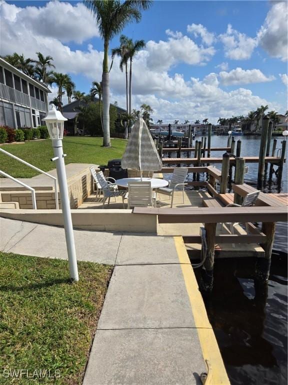 view of home's community with a yard, a dock, and a water view