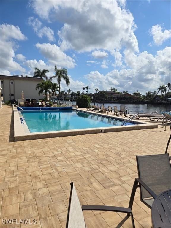 view of swimming pool featuring a water view and a patio area