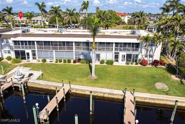 rear view of property featuring a water view, a yard, and a sunroom