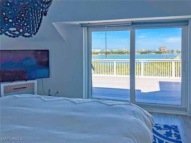 bedroom with wood-type flooring, a water view, and access to exterior