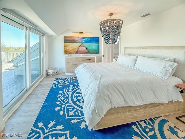 bedroom featuring an inviting chandelier, access to exterior, and hardwood / wood-style floors