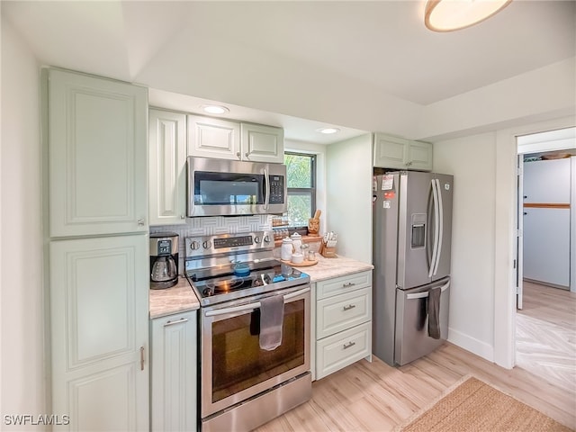 kitchen with stainless steel appliances, decorative backsplash, and light hardwood / wood-style flooring