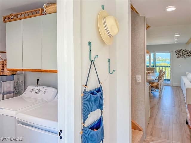 laundry room featuring cabinets, washer and clothes dryer, and light wood-type flooring