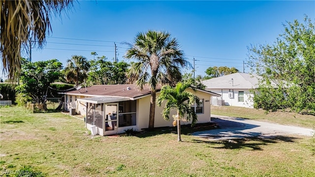 rear view of house with a yard and a sunroom