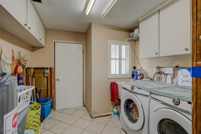 laundry area with cabinets, washer and dryer, light tile patterned floors, and a textured ceiling