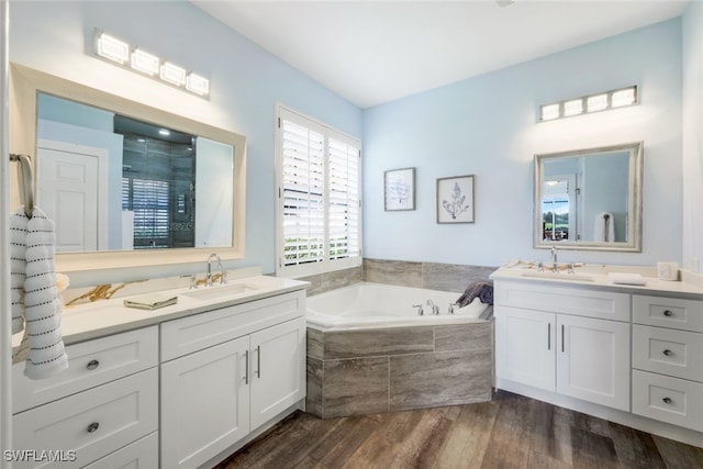bathroom featuring two vanities, a sink, a stall shower, and wood finished floors