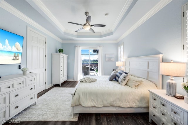 bedroom with dark wood-type flooring, a tray ceiling, ornamental molding, and ceiling fan