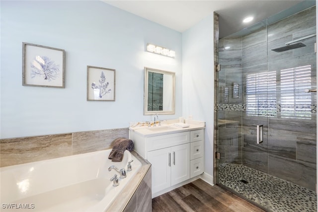 bathroom featuring vanity, a stall shower, recessed lighting, a bath, and wood finished floors