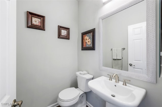 bathroom with a sink, toilet, and baseboards