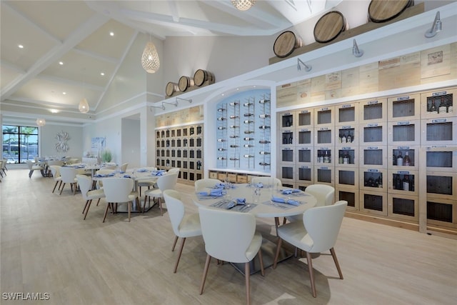 dining space with light wood finished floors, high vaulted ceiling, and beam ceiling