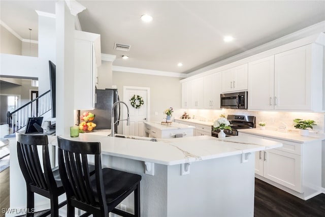 kitchen with a peninsula, visible vents, decorative backsplash, crown molding, and appliances with stainless steel finishes