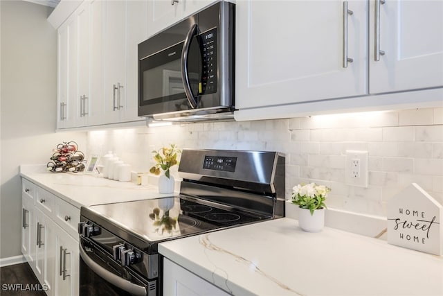 kitchen featuring tasteful backsplash, light stone counters, white cabinets, electric range oven, and stainless steel microwave