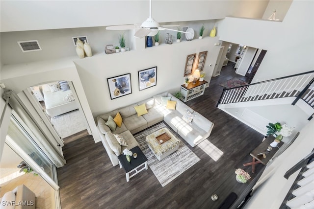 living area with wood finished floors, visible vents, stairs, and ceiling fan