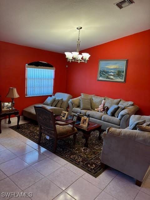 tiled living room with vaulted ceiling and a notable chandelier