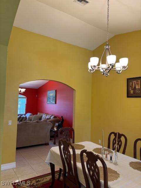 tiled dining space featuring lofted ceiling and a notable chandelier