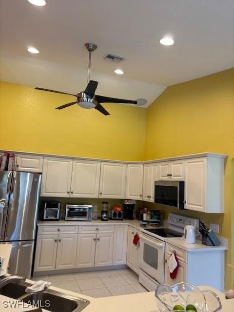 kitchen featuring high vaulted ceiling, sink, white cabinets, light tile patterned floors, and stainless steel appliances