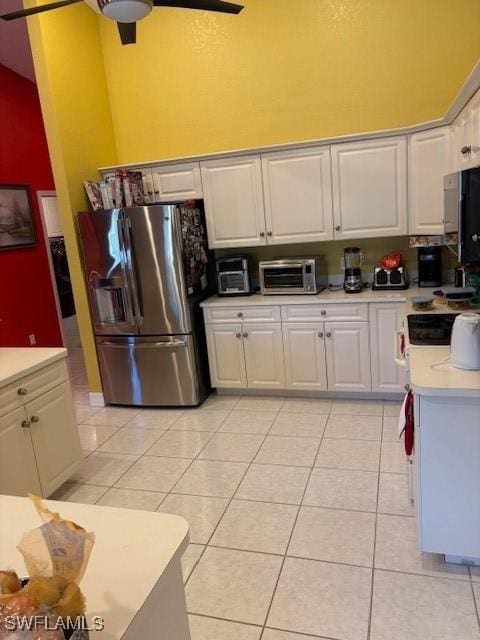 kitchen with stainless steel refrigerator with ice dispenser, white cabinetry, a high ceiling, and light tile patterned floors