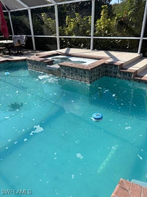 view of swimming pool featuring an in ground hot tub, a lanai, and a patio