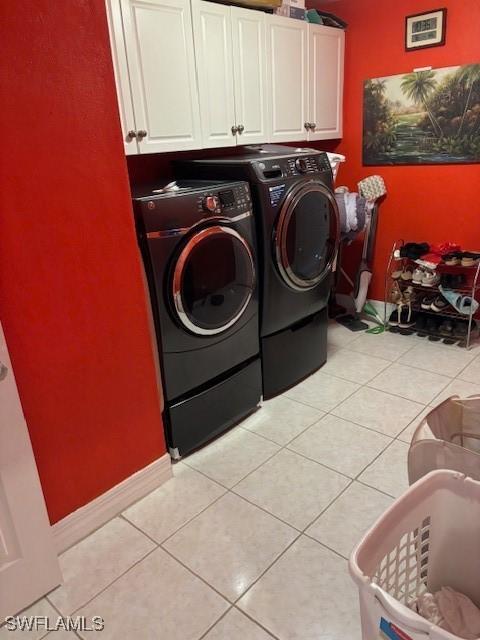 laundry area featuring washer and dryer, cabinets, and light tile patterned flooring