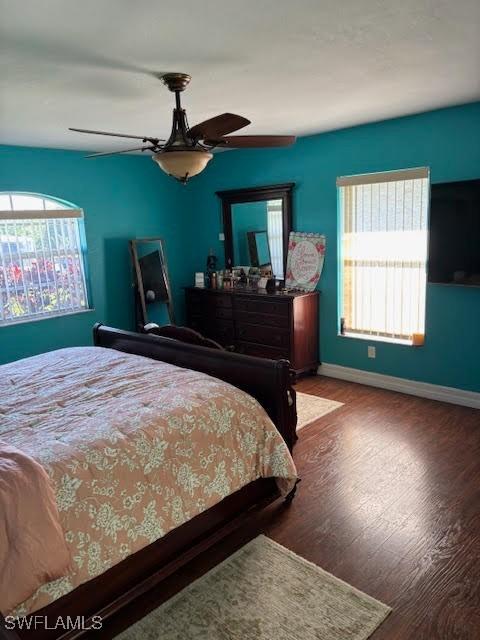 bedroom with ceiling fan, wood-type flooring, and multiple windows