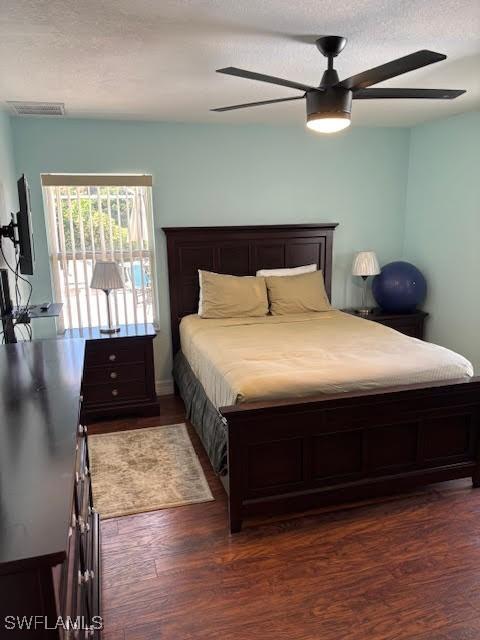 bedroom featuring ceiling fan, dark hardwood / wood-style flooring, and a textured ceiling