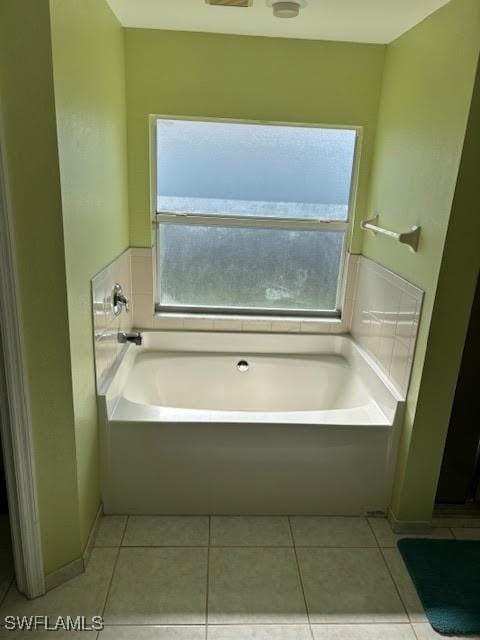 bathroom with tile patterned floors and a tub to relax in